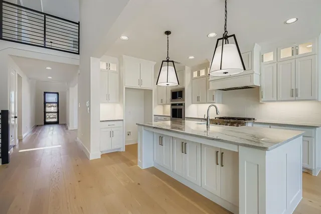 a kitchen with stainless steel appliances granite countertop a sink a stove a refrigerator and white cabinets