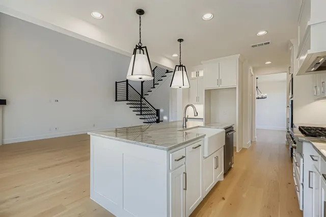 a kitchen with stainless steel appliances granite countertop a sink a stove and a wooden floor