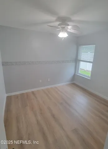 an empty room with a chandelier fan and windows
