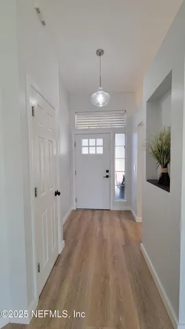 a view of a hallway with wooden floor and a chandelier