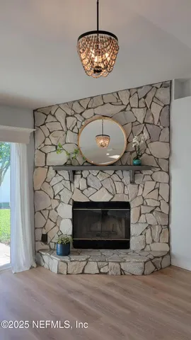 a living room with a fireplace a chandelier and a wooden floor