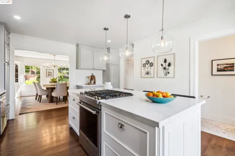 a kitchen with kitchen island granite countertop a sink a stove a dining table and chairs