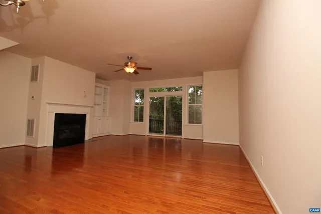 a view of an empty room with wooden floor and a fireplace