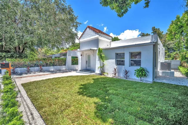 a front view of a house with a yard and potted plants