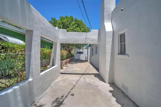 a backyard of a house with table and chairs under an umbrella