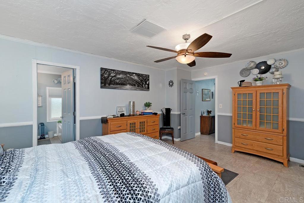 18218 Paradise Mountain Road Valley Center, CA 92082 - Photo 22 of 37 a bedroom with a bed and a chandelier