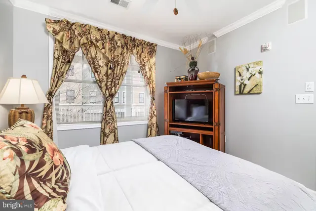 a bedroom with a bed and a flat tv screen on the dresser