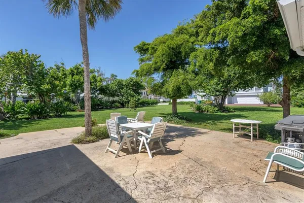 a view of a patio with table and chairs potted plants and palm tree