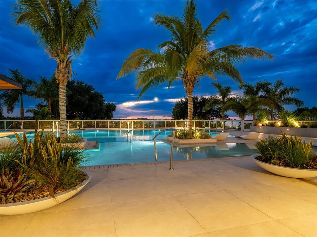 1020 Sunset Point Road, Unit 511 Clearwater, FL 33755 - Photo 13 of 99 a view of swimming pool with table and chairs under an umbrella