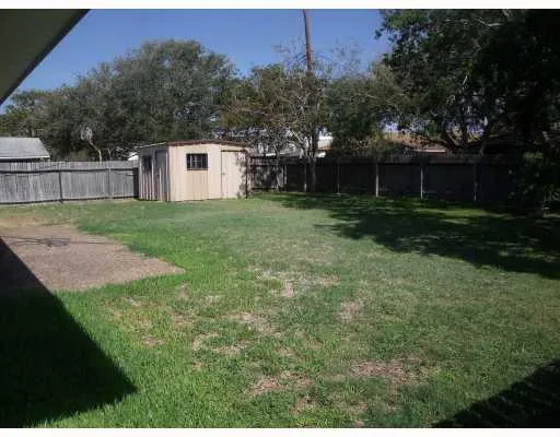 a view of a backyard with large trees and wooden fence