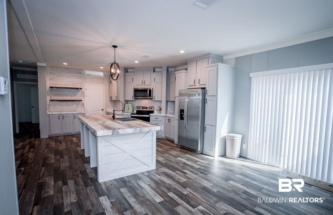 19180 Horseshoe Circle Seminole, AL 36574 - Photo 12 of 38 Kitchen featuring a kitchen island with sink, appliances with stainless steel finishes, open shelves, pendant lighting, and dark wood-style flooring