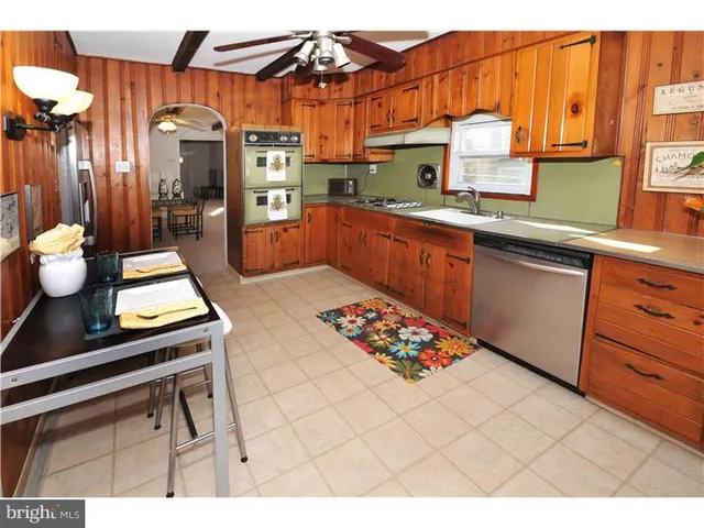 a kitchen with stainless steel appliances a sink a stove top oven a chimney and a center island
