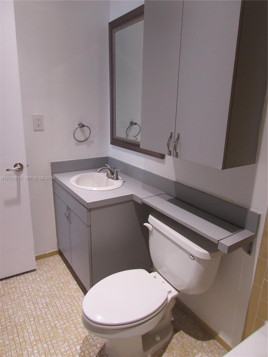 5555 Ludlam Road, Unit 23 South Miami, FL 33155 - Photo 16 of 25 a bathroom with a toilet sink and mirror