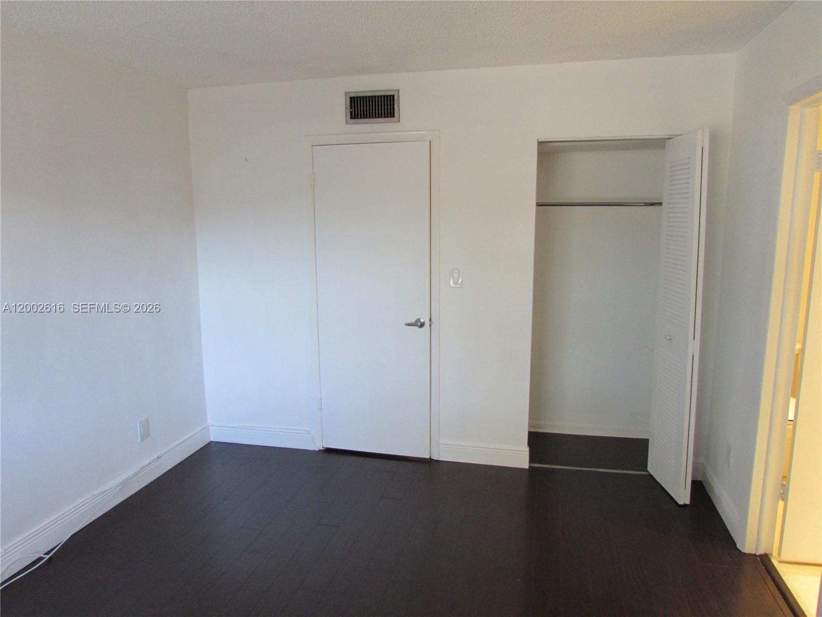 5555 Ludlam Road, Unit 23 South Miami, FL 33155 - Photo 10 of 25 an empty room with wooden floor and windows
