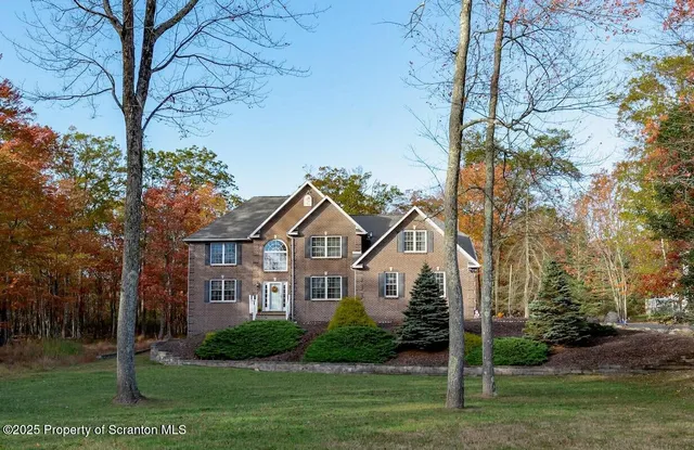 a front view of a house with a garden and trees