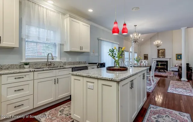 a kitchen with granite countertop a sink dishwasher and white cabinets with wooden floor