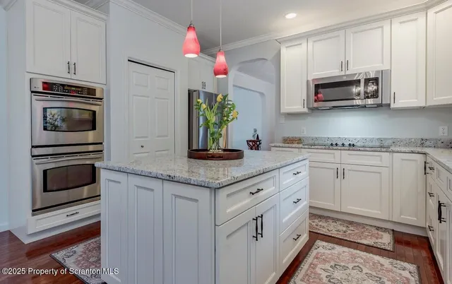 a kitchen with granite countertop white cabinets and stainless steel appliances