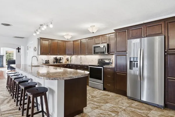 a kitchen with kitchen island granite countertop a sink stove and refrigerator