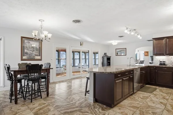 a kitchen with stainless steel appliances granite countertop a stove top oven a dining table and chairs with wooden floor