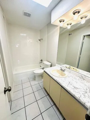 a bathroom with a granite countertop sink a toilet and a mirror