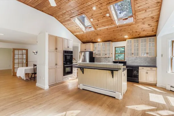 a kitchen with stainless steel appliances kitchen island granite countertop a table chairs and a refrigerator