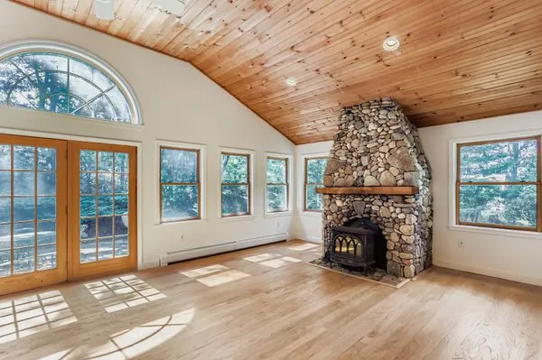 an empty room with windows a fireplace and wooden floor