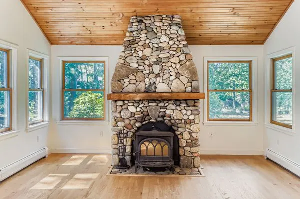 an empty room with wooden floor a fireplace and windows