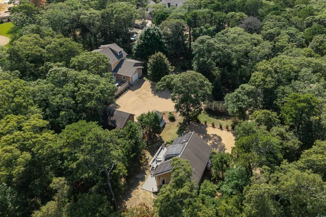 an aerial view of residential house with outdoor space and trees all around