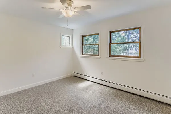 an empty room with windows and fan