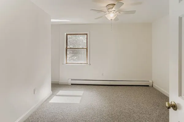 an empty room with windows and fan