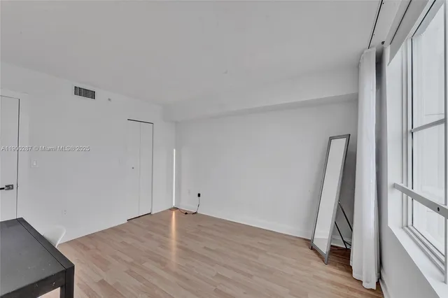 an empty room with wooden floor and a window