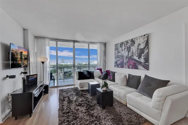 a living room with furniture a flat screen tv and a floor to ceiling window