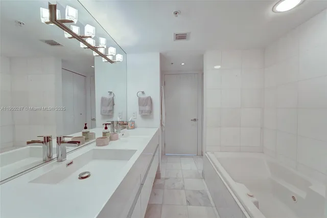 a bathroom with a tub a sink shower and mirror