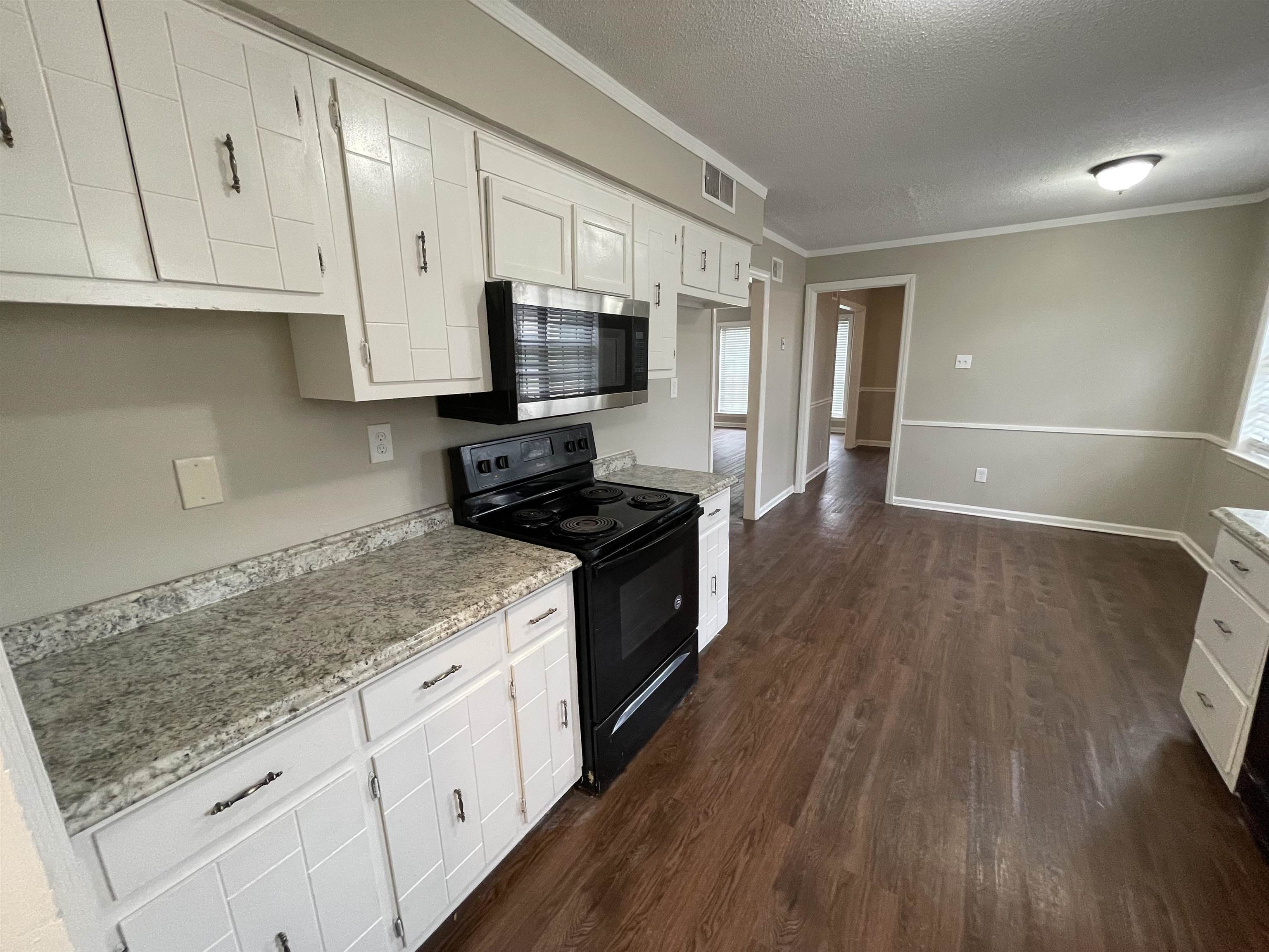 5414 Maple Ridge Road Memphis, TN 38134 - Photo 12 of 23 Kitchen with white cabinetry, crown molding, a textured ceiling, dark hardwood / wood-style flooring, and black electric range oven