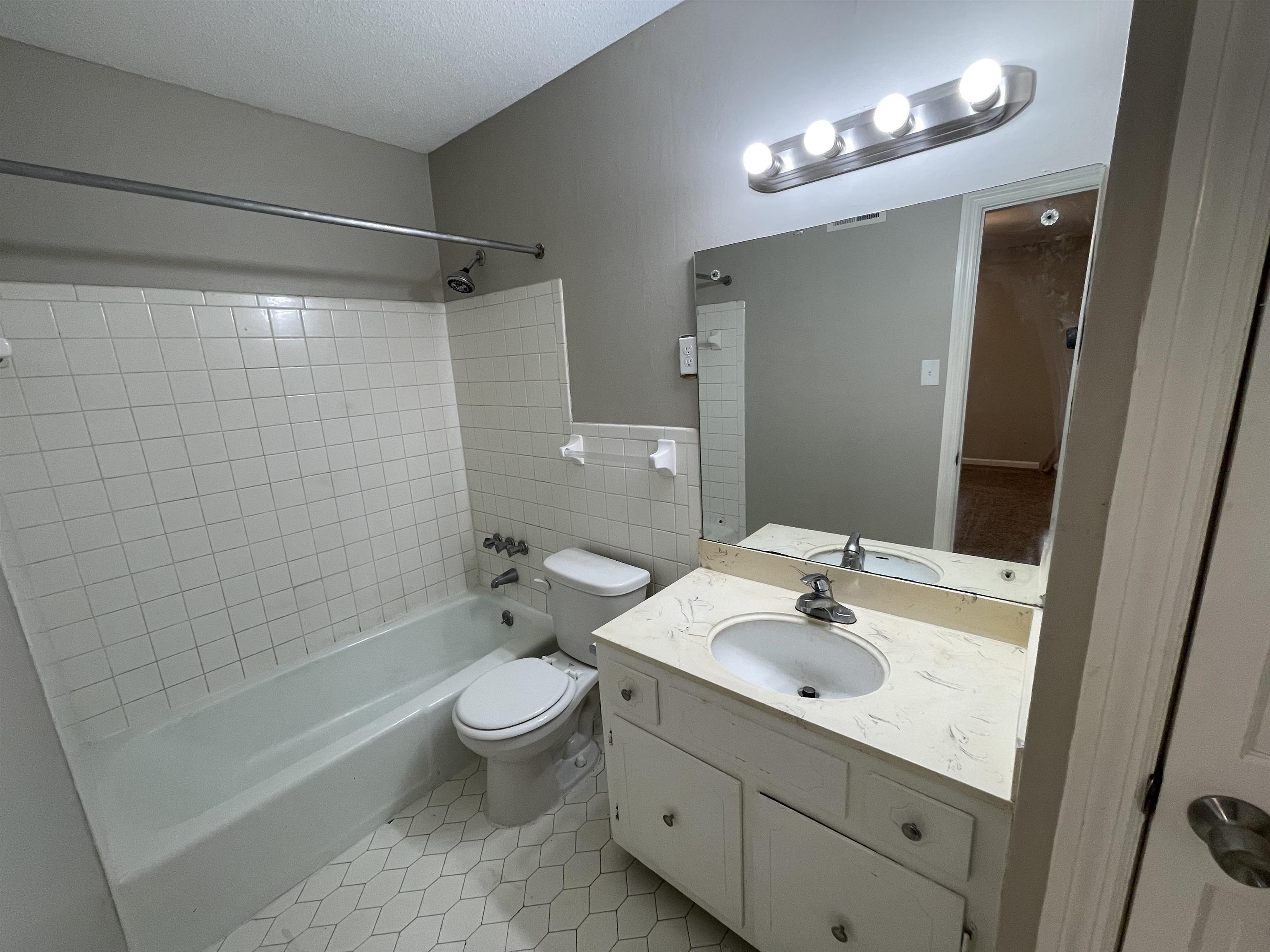 5414 Maple Ridge Road Memphis, TN 38134 - Photo 17 of 23 Full bathroom with tile patterned flooring, a textured ceiling, toilet, vanity, and tiled shower / bath combo