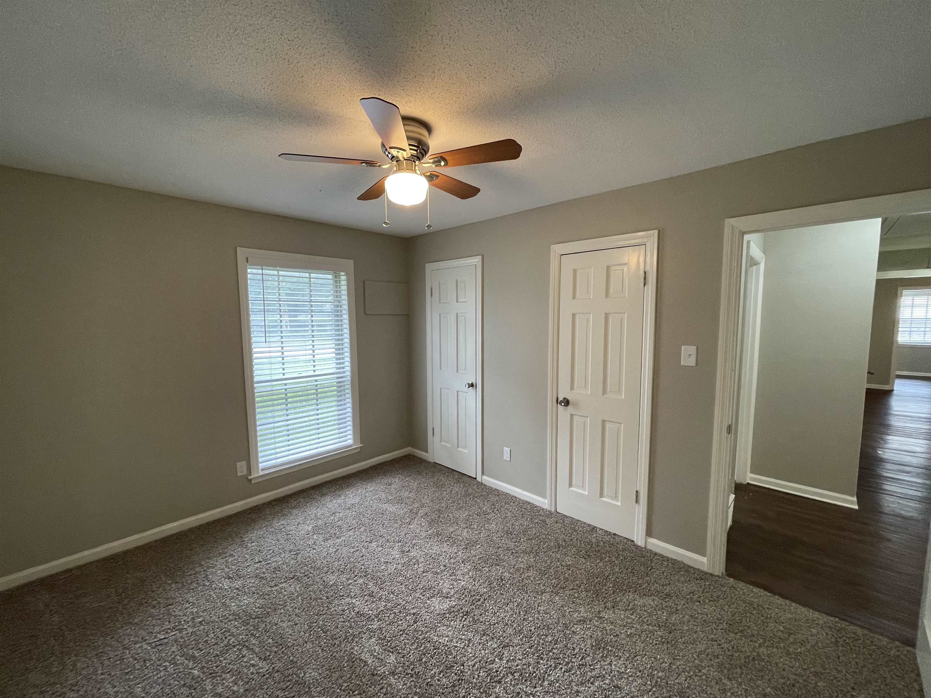 5414 Maple Ridge Road Memphis, TN 38134 - Photo 18 of 23 Unfurnished bedroom featuring two closets, a textured ceiling, ceiling fan, and dark carpet