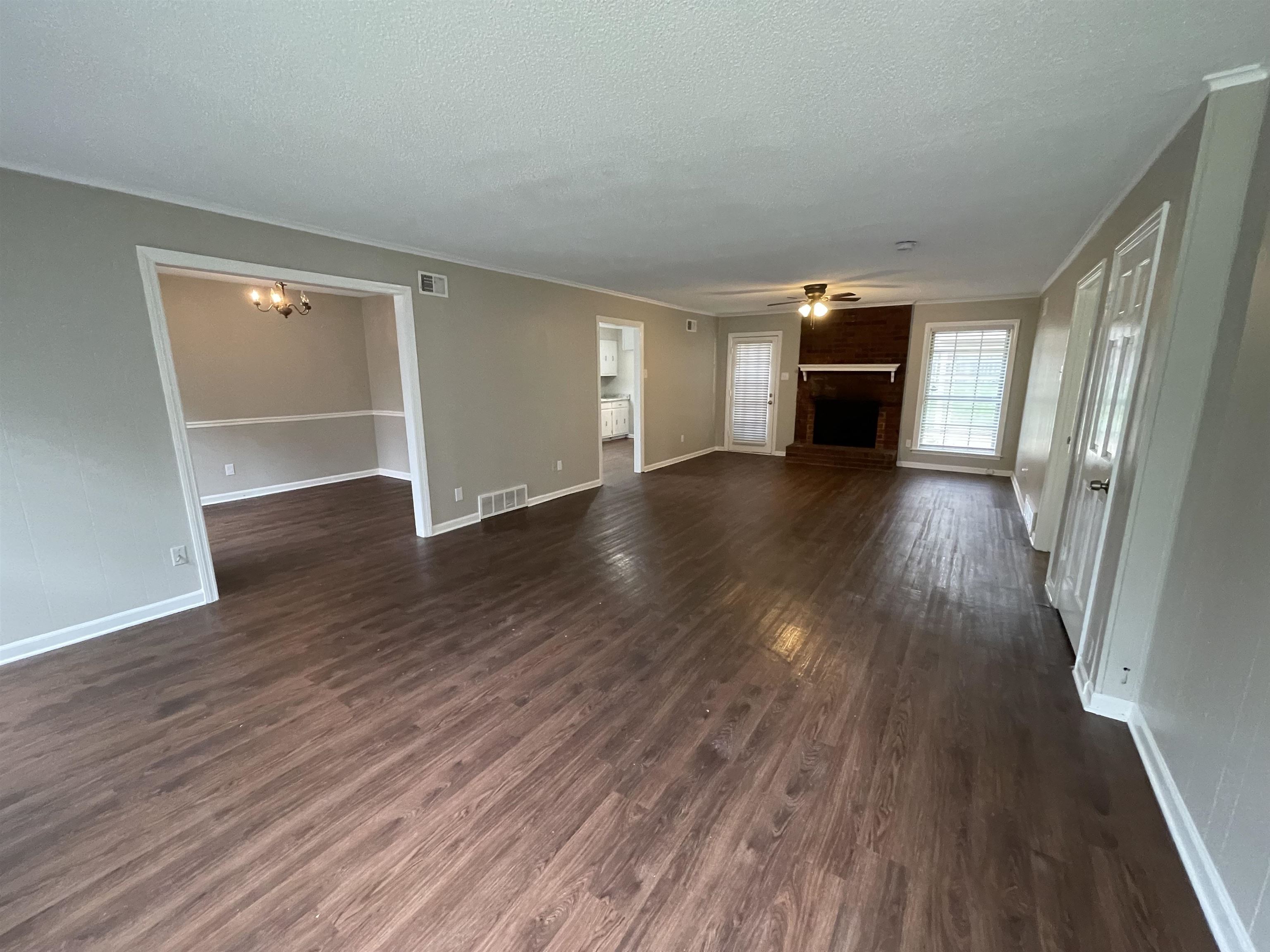5414 Maple Ridge Road Memphis, TN 38134 - Photo 5 of 23 Unfurnished living room with dark hardwood / wood-style floors, ceiling fan with notable chandelier, ornamental molding, and a textured ceiling