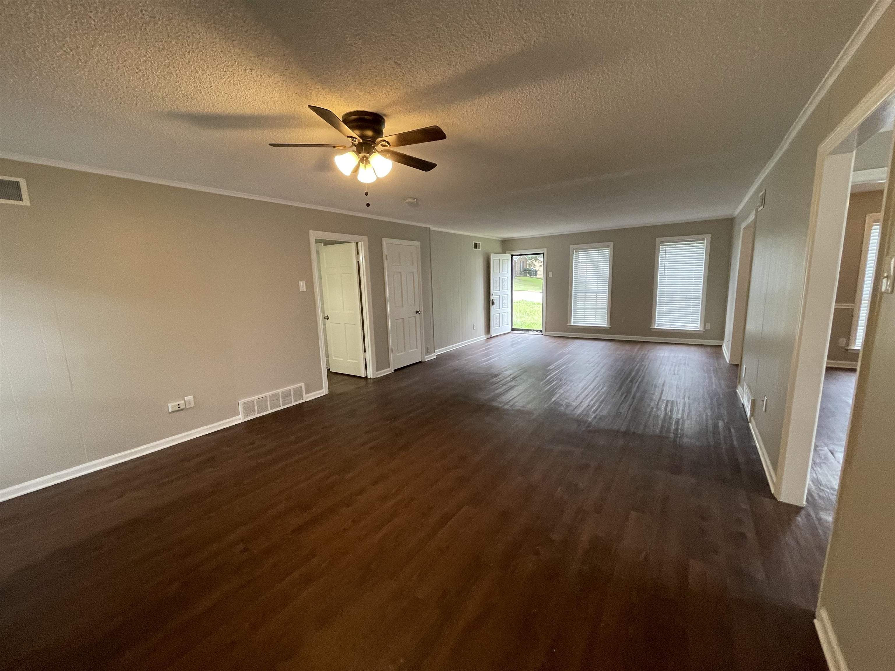 5414 Maple Ridge Road Memphis, TN 38134 - Photo 7 of 23 Spare room featuring ceiling fan, a textured ceiling, dark hardwood / wood-style flooring, and ornamental molding
