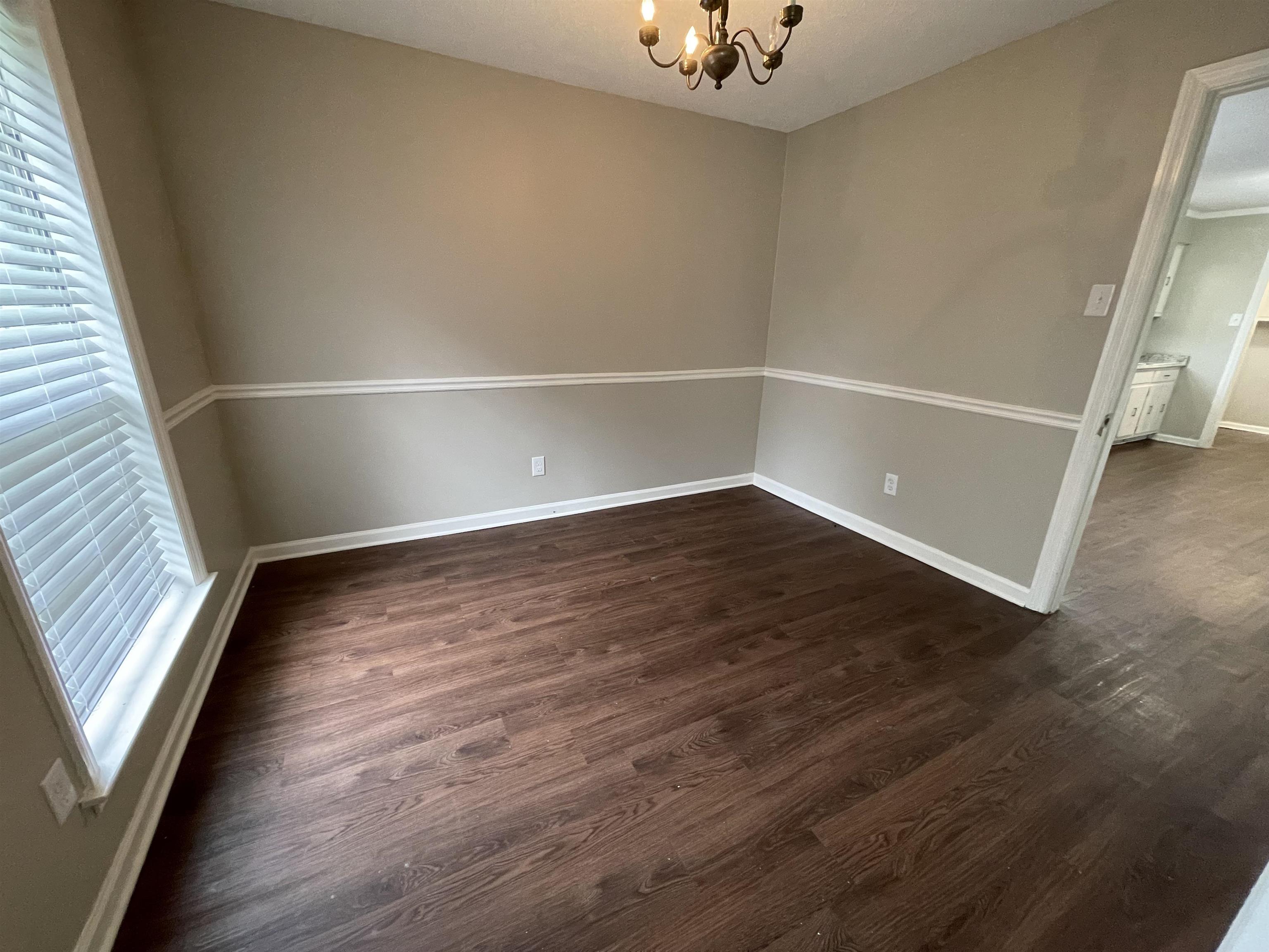 5414 Maple Ridge Road Memphis, TN 38134 - Photo 8 of 23 Empty room with a chandelier, dark hardwood / wood-style floors, and a healthy amount of sunlight