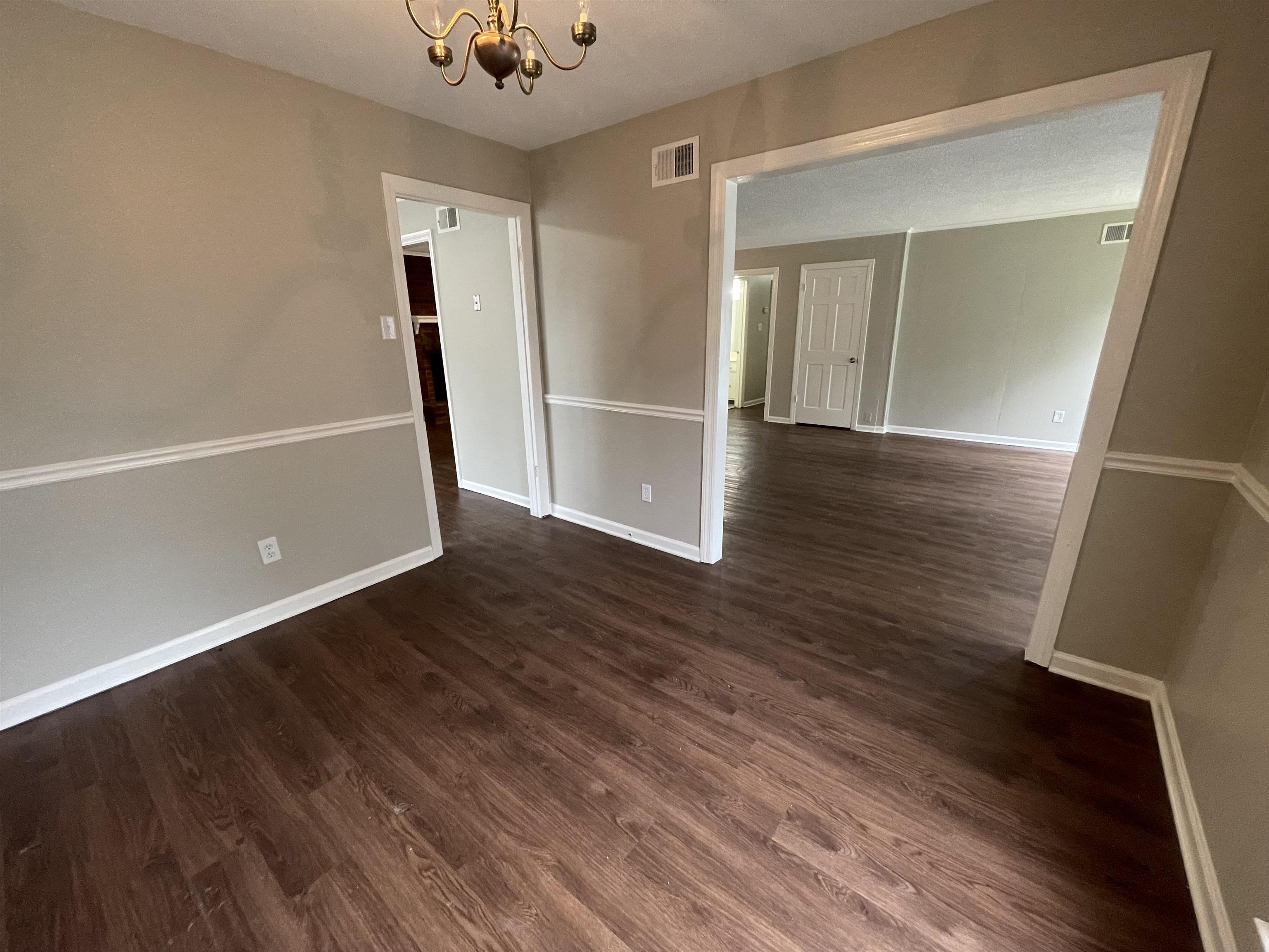 5414 Maple Ridge Road Memphis, TN 38134 - Photo 9 of 23 Empty room featuring wood-type flooring and a notable chandelier