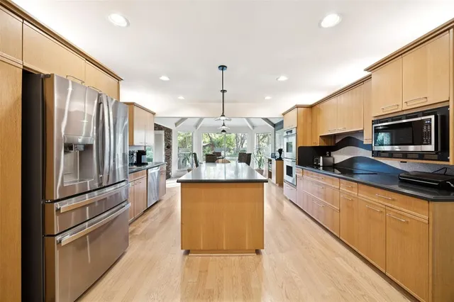 a kitchen with stainless steel appliances granite countertop a sink a stove and chairs
