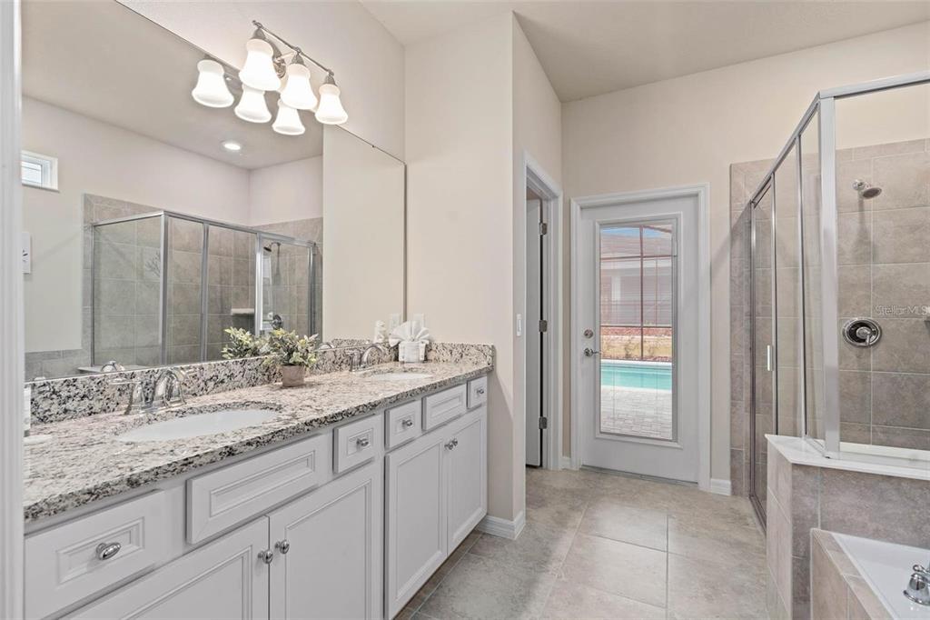 7180 Oakmoss Loop Davenport, FL 33837 - Photo 16 of 29 a bathroom with a granite countertop sink a large mirror and a shower