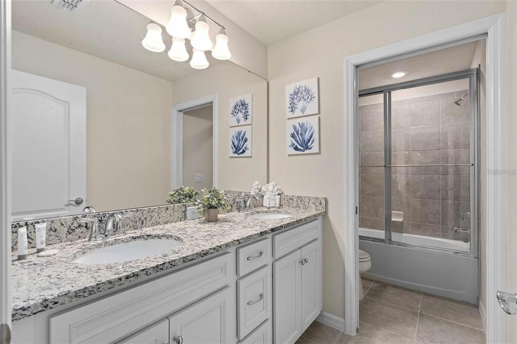 7180 Oakmoss Loop Davenport, FL 33837 - Photo 22 of 29 a bathroom with a granite countertop sink a toilet and shower