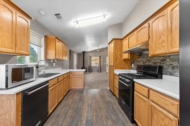 a large kitchen with stainless steel appliances granite countertop a stove a sink and a microwave