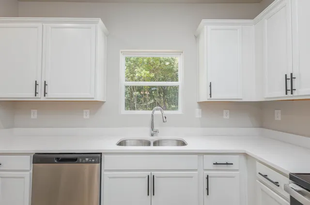 a kitchen with white cabinets and a window