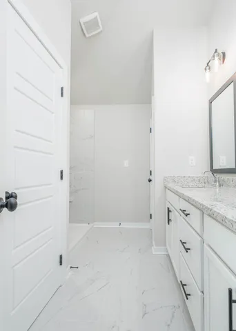 a bathroom with a granite countertop sink and white cabinets