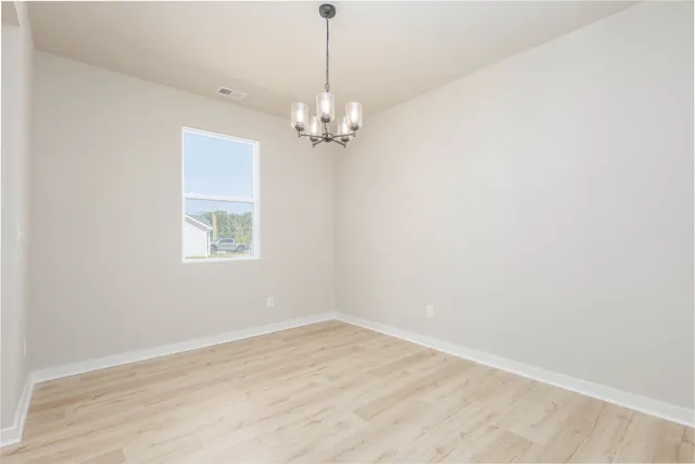 a view of a room with a chandelier fan and a wooden floor