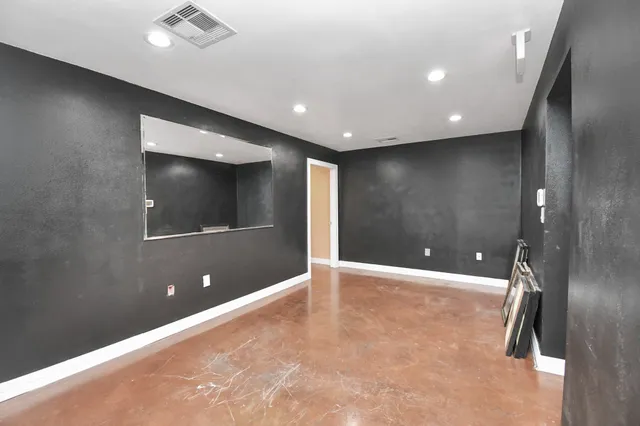 an empty room with wooden floor and mirror