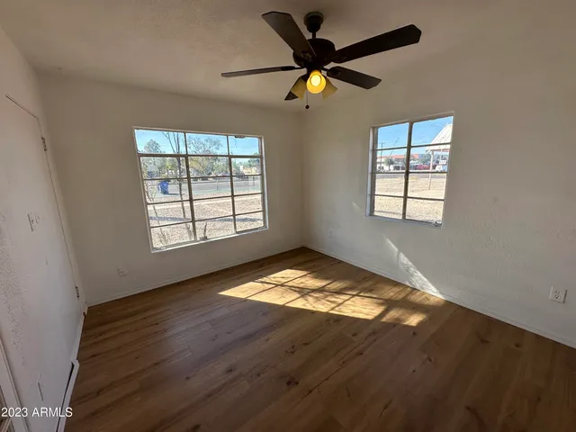a view of empty room with wooden floor and fan