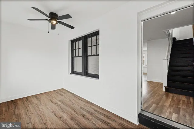 a view of a room with wooden floor staircase and a ceiling fan